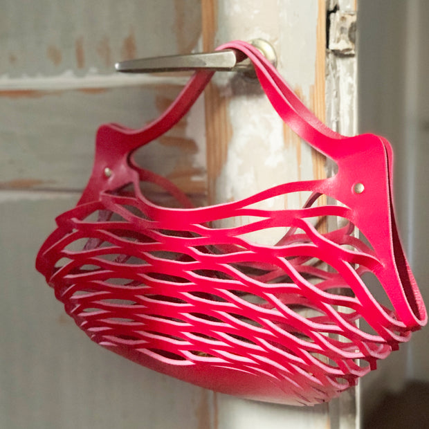 Innovative Tasche, Formgebung durch Lasercut Technik aus vegetabil gegerbtem Leder, made in Germany, Farbe Himbeer. Das Netz macht die Tasche flexibel in der Größe. 